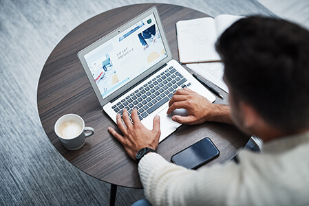 Male website designer developing landing pages for a business website using a laptop.