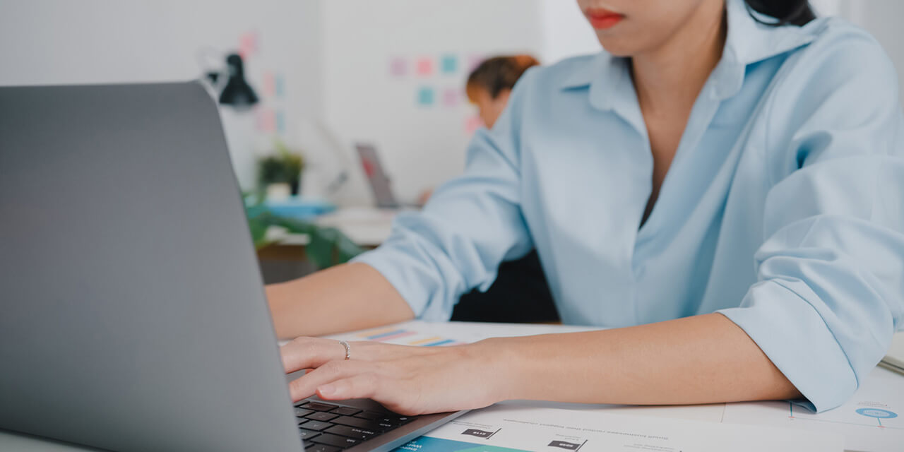 Young businesswoman in an office setup designing a blog using a laptop.