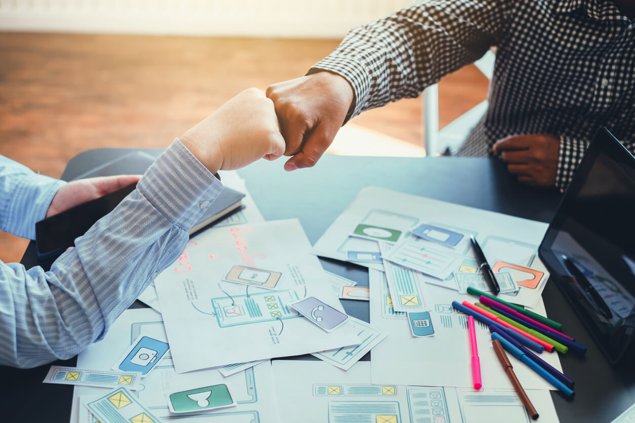 Two web designers fist-bumping, showing agreement on their web design and website optimization processes.