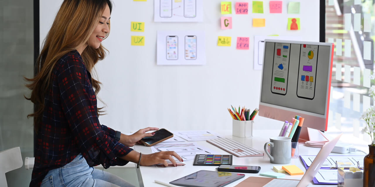 Female website designer testing a web design's mobile readiness.